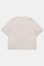 Vista trasera de polo boxy fit para hombre en color arena. Con cuello redondo, manga corta y estampado a la altura del hombro. Estilo urbano.