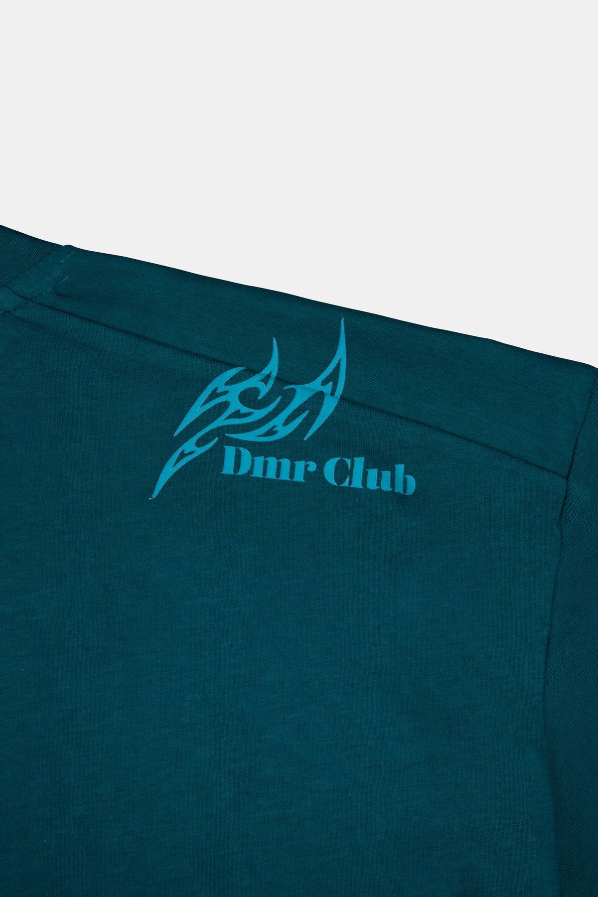 Detalle de estampado DTF a la altura del hombro en polo boxy fit manga corta para hombre en color verde esmeralda. 